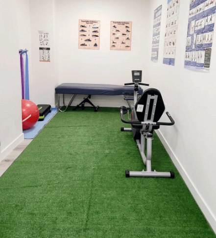 The exercise and rehabilitation room at the clinic, with a treatment bench, exercise bike and stretch charts