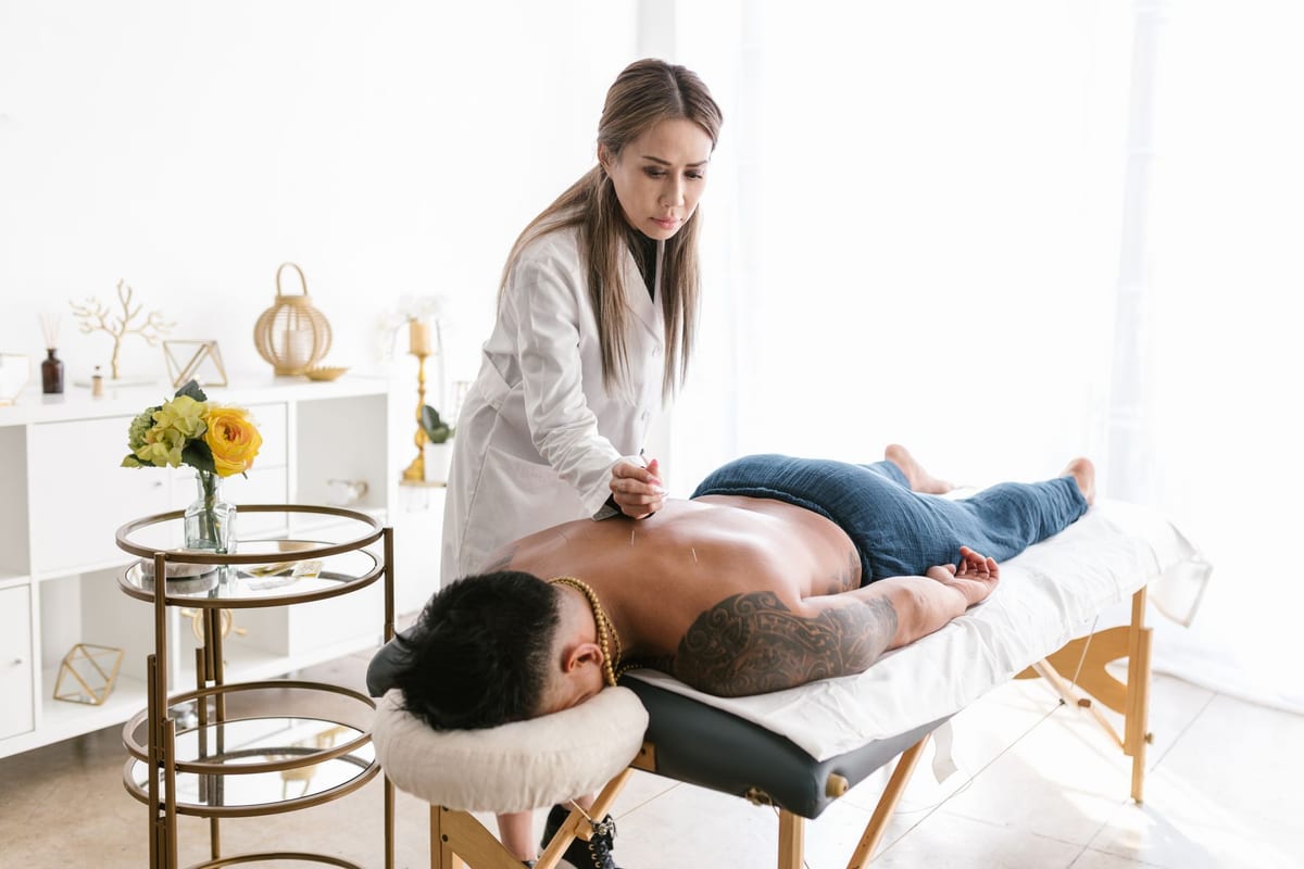 A clinician placing acupuncture needles along a patient's back